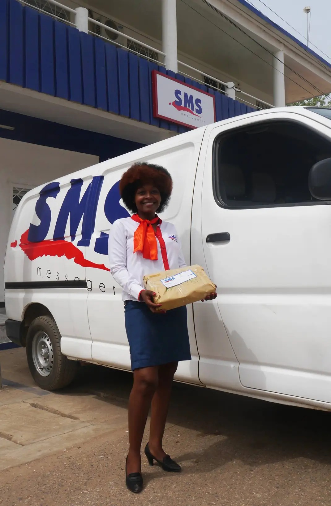 Employée SMS livrant un colis devant le véhicule SMS